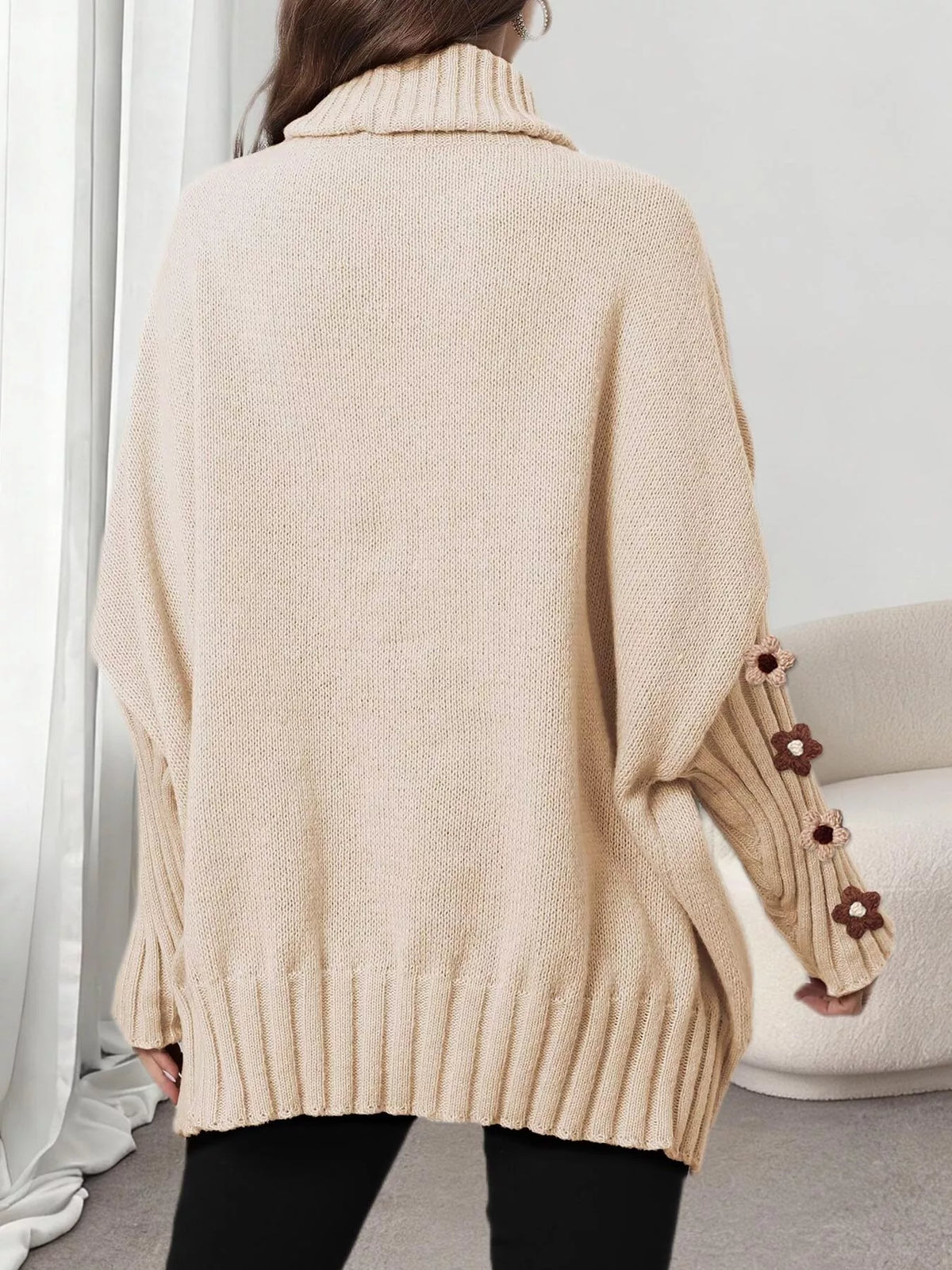 View 4 of the oversized turtleneck sweater with floral appliqué on the sleeves and ribbed collar and cuffs.