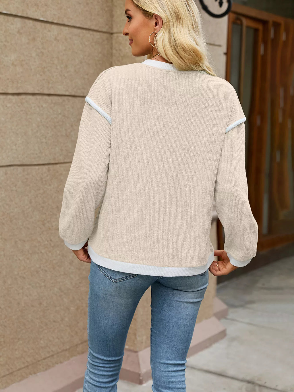 View 6 of the beige dropped-shoulder V-neck knit sweater with white binding at the neck, cuffs, and hem.