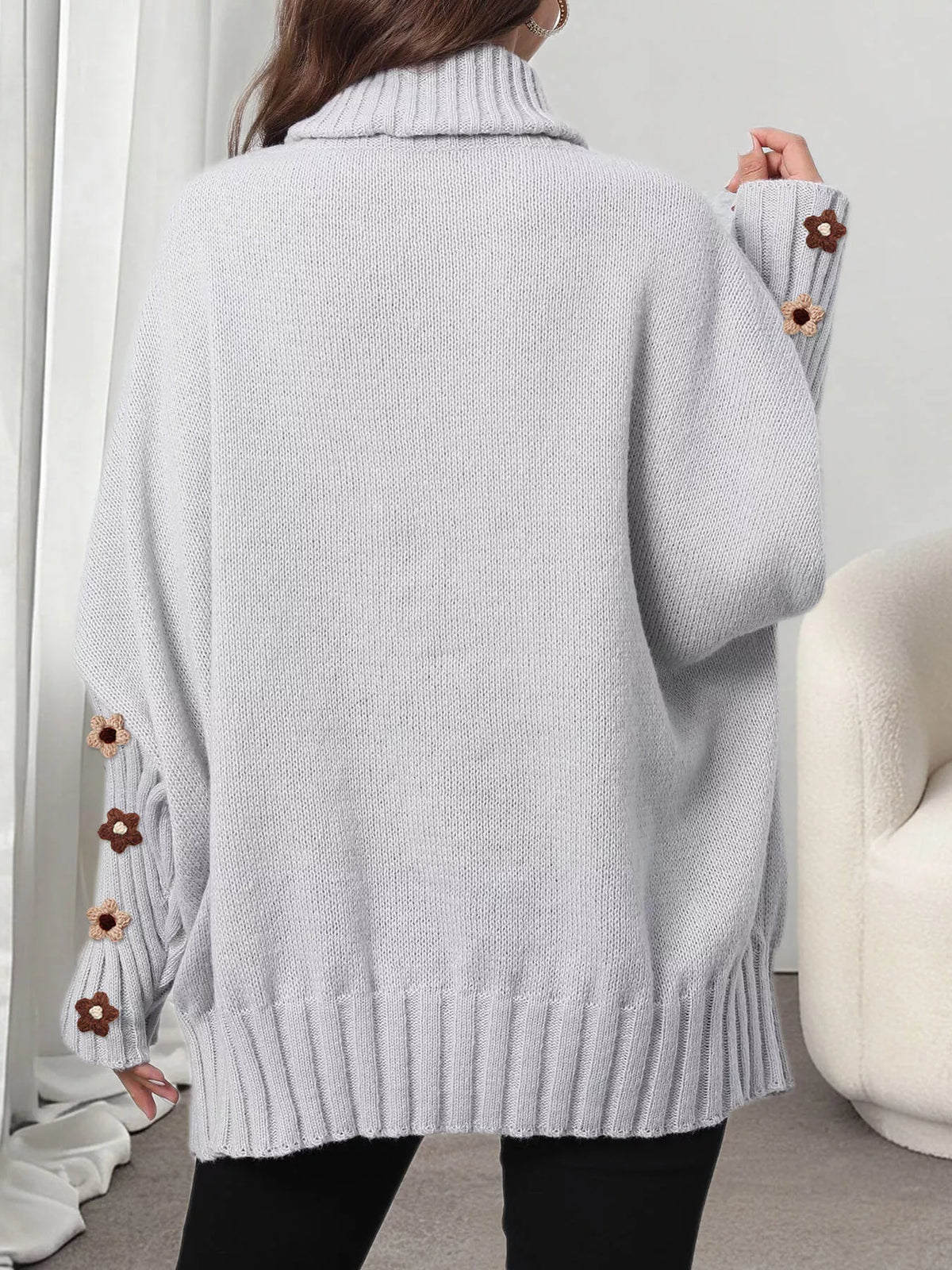 View 13 of the oversized turtleneck sweater with floral appliqué on the sleeves and ribbed collar and cuffs.