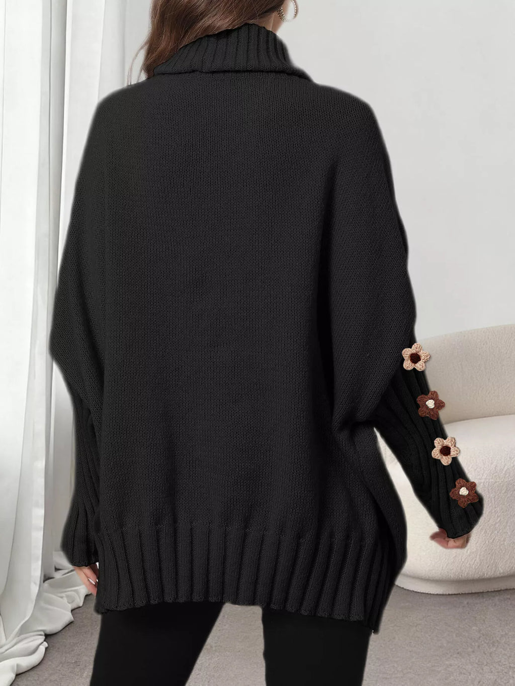 View 8 of the oversized turtleneck sweater with floral appliqué on the sleeves and ribbed collar and cuffs.