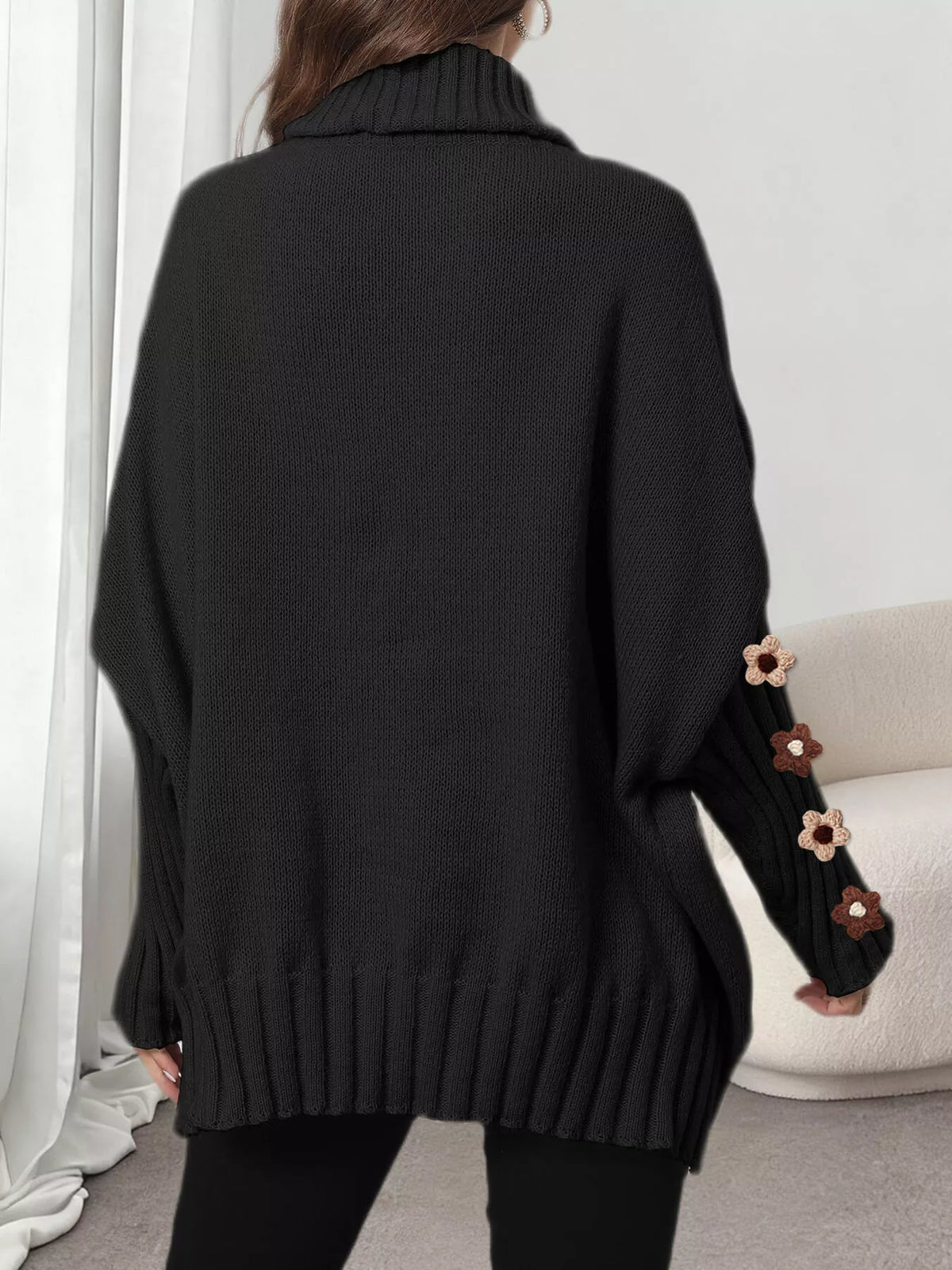 View 8 of the oversized turtleneck sweater with floral appliqué on the sleeves and ribbed collar and cuffs.