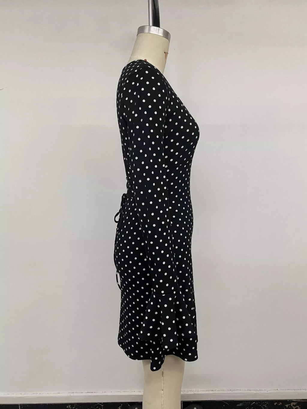 View 13 of the black long-sleeve polka-dot mini dress with a deep V and ruffled cuffs.