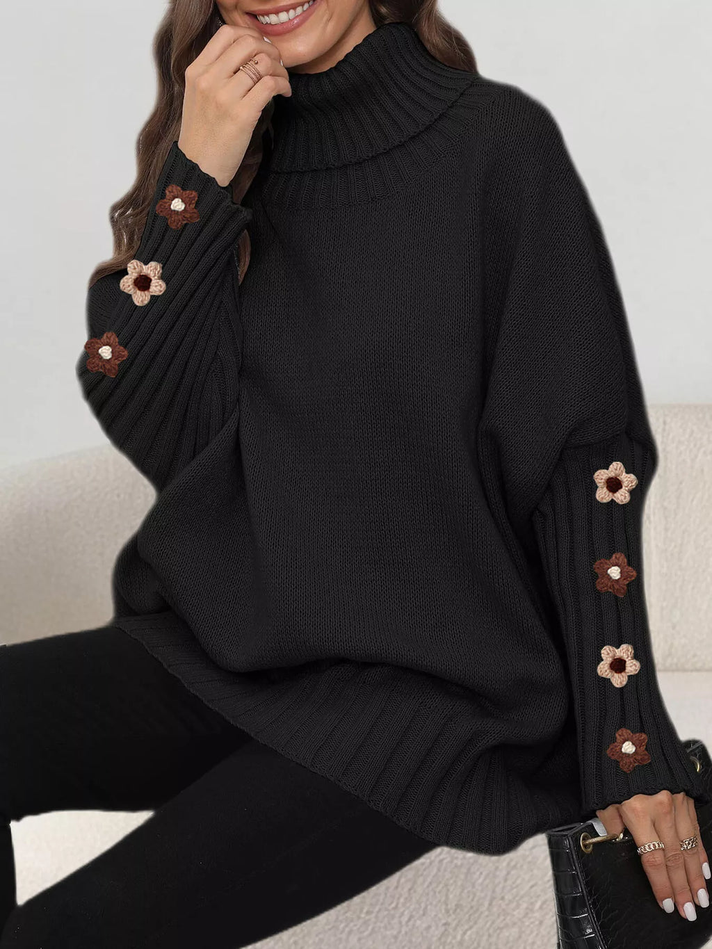 View 6 of the oversized turtleneck sweater with floral appliqué on the sleeves and ribbed collar and cuffs.