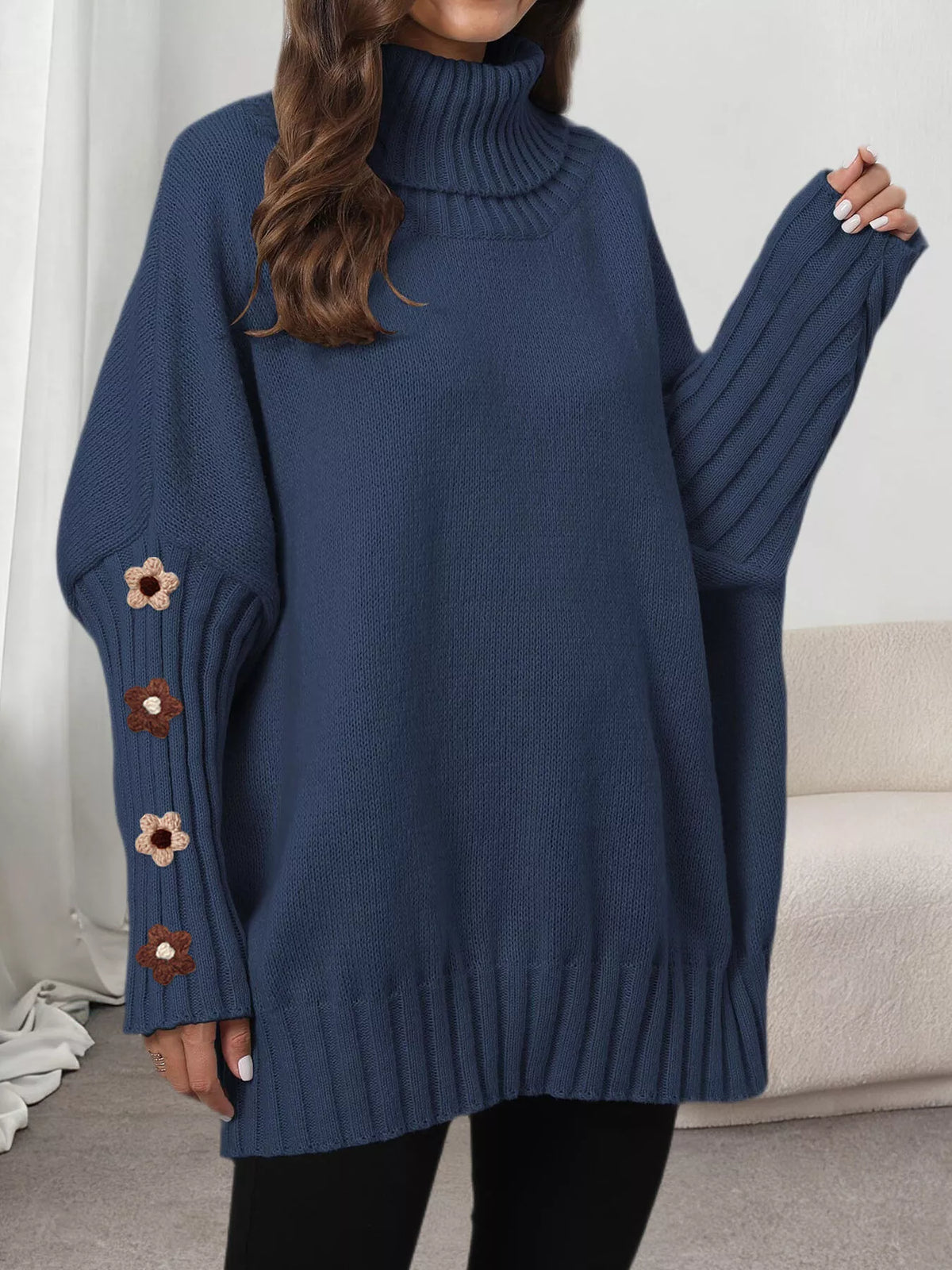 View 14 of the oversized turtleneck sweater with floral appliqué on the sleeves and ribbed collar and cuffs.