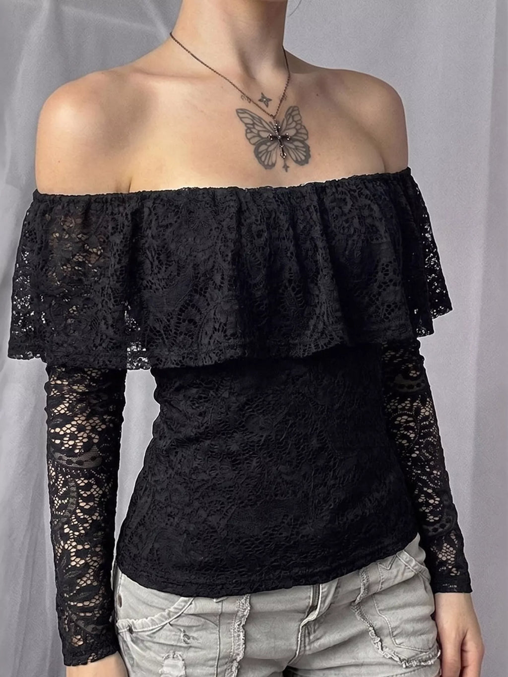 View 4 of the black off-the-shoulder crop top with floral lace at the neck and sleeves.