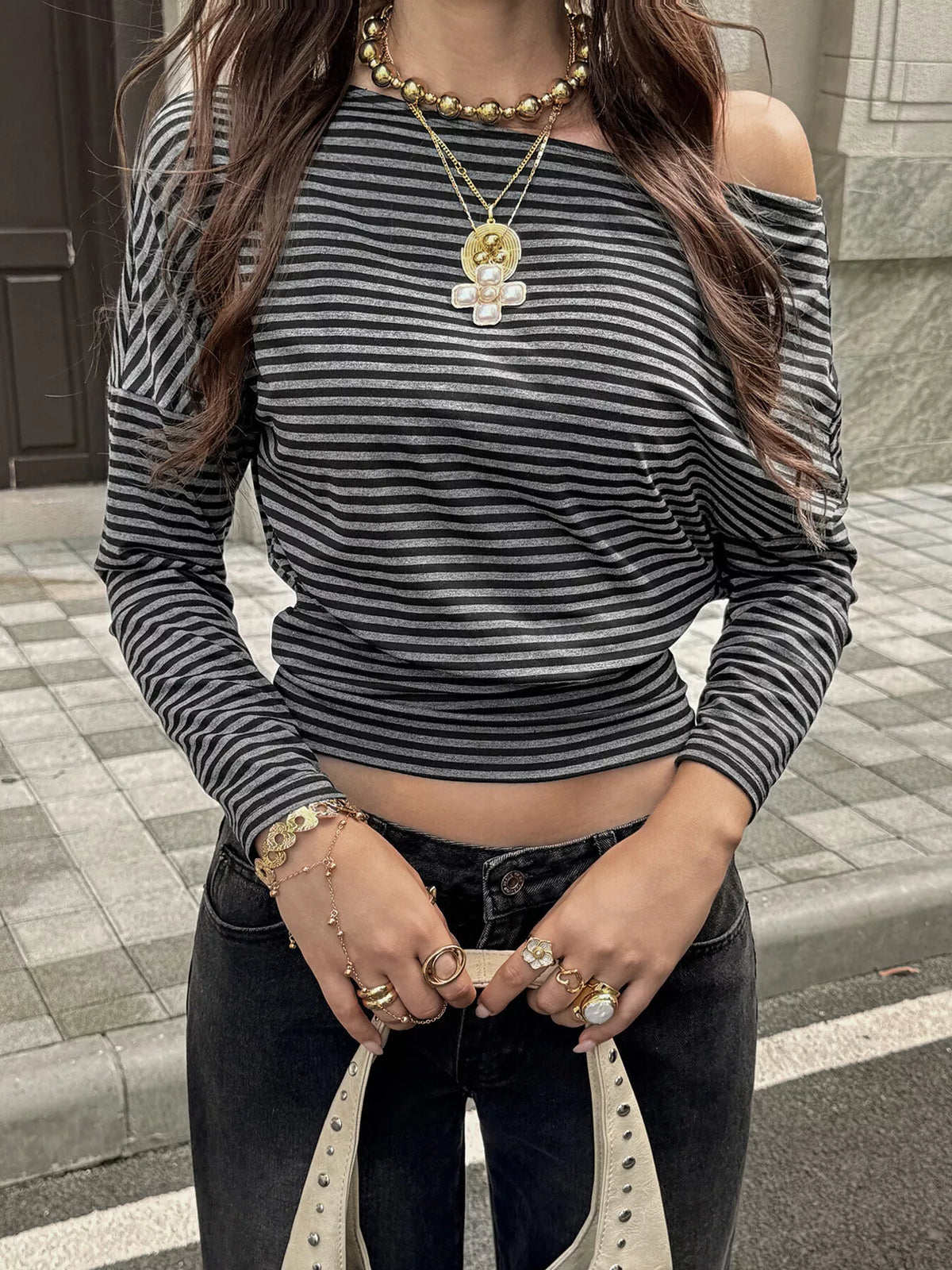 View 2 of the black-and-gray striped cropped top worn off one shoulder.