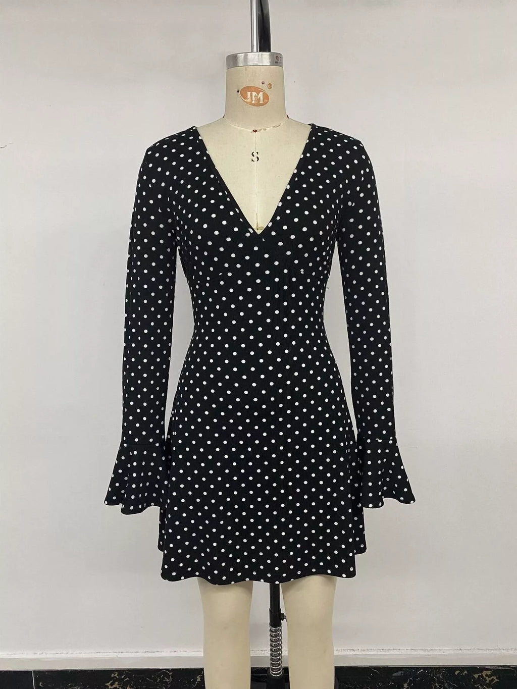 View 12 of the black long-sleeve polka-dot mini dress with a deep V and ruffled cuffs.