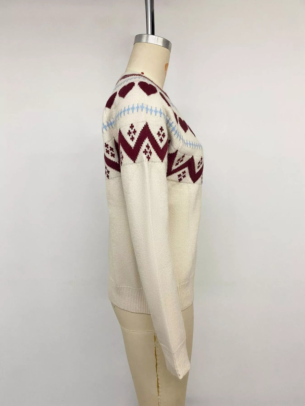 View 13 of the crewneck sweater with a heart pattern through the knit.