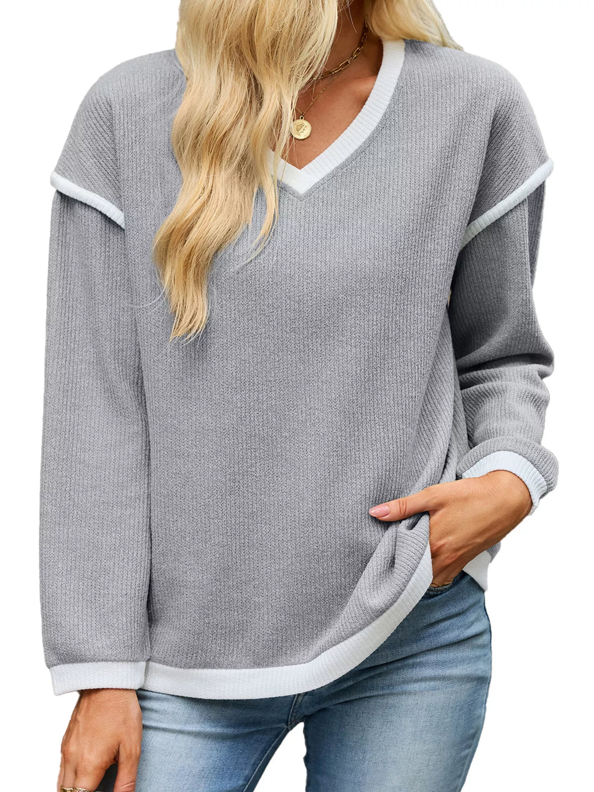 View 23 of the beige dropped-shoulder V-neck knit sweater with white binding at the neck, cuffs, and hem.