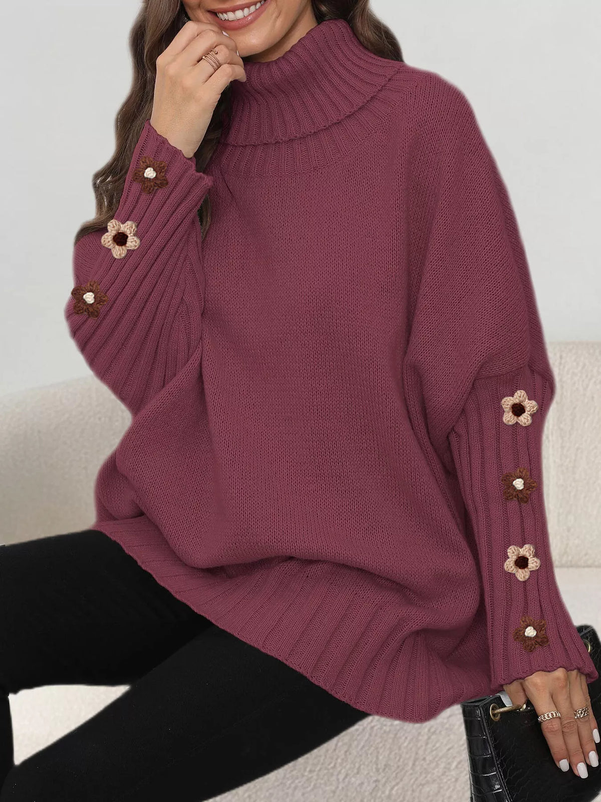 View 16 of the oversized turtleneck sweater with floral appliqué on the sleeves and ribbed collar and cuffs.