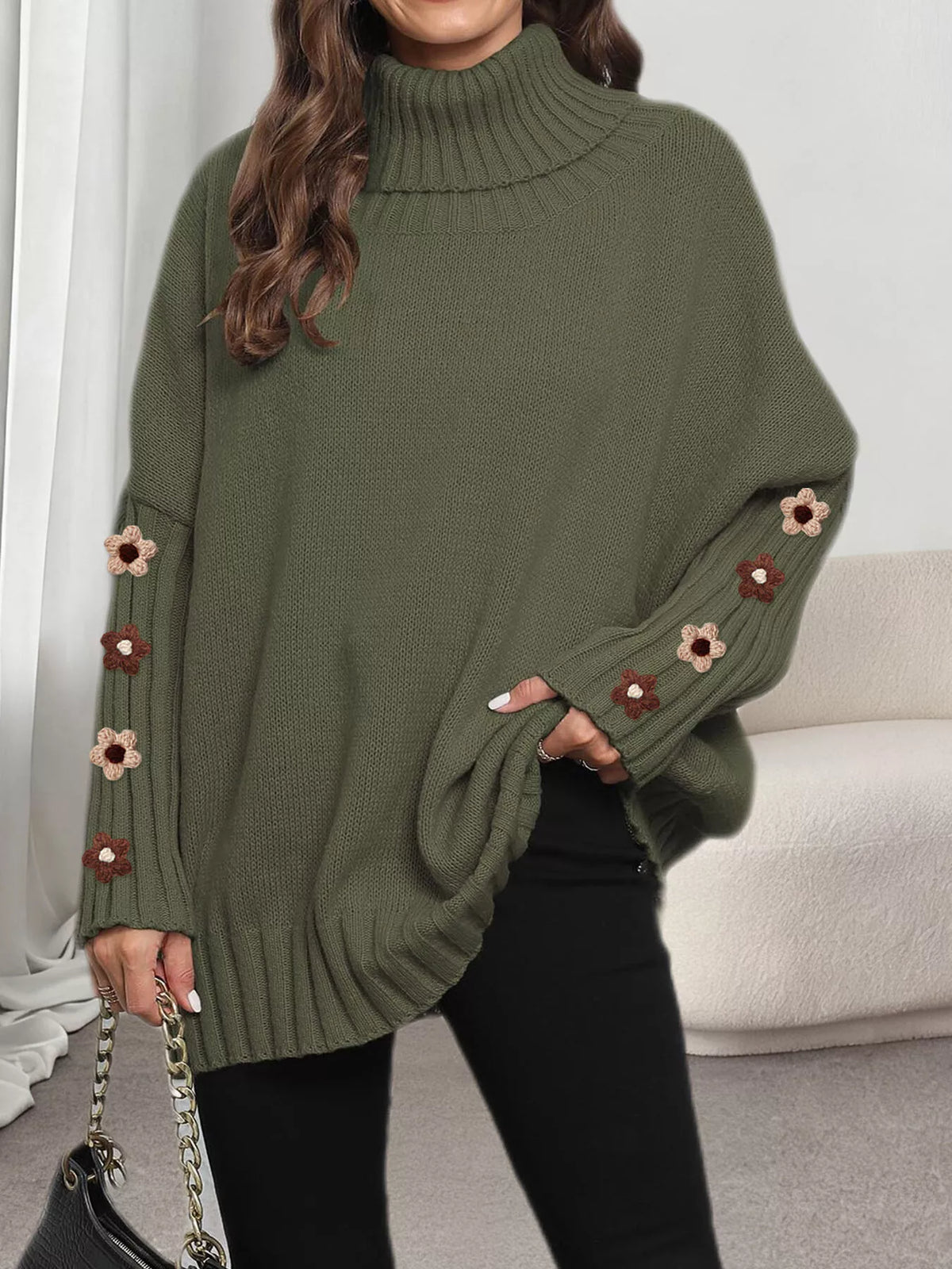 View 18 of the oversized turtleneck sweater with floral appliqué on the sleeves and ribbed collar and cuffs.