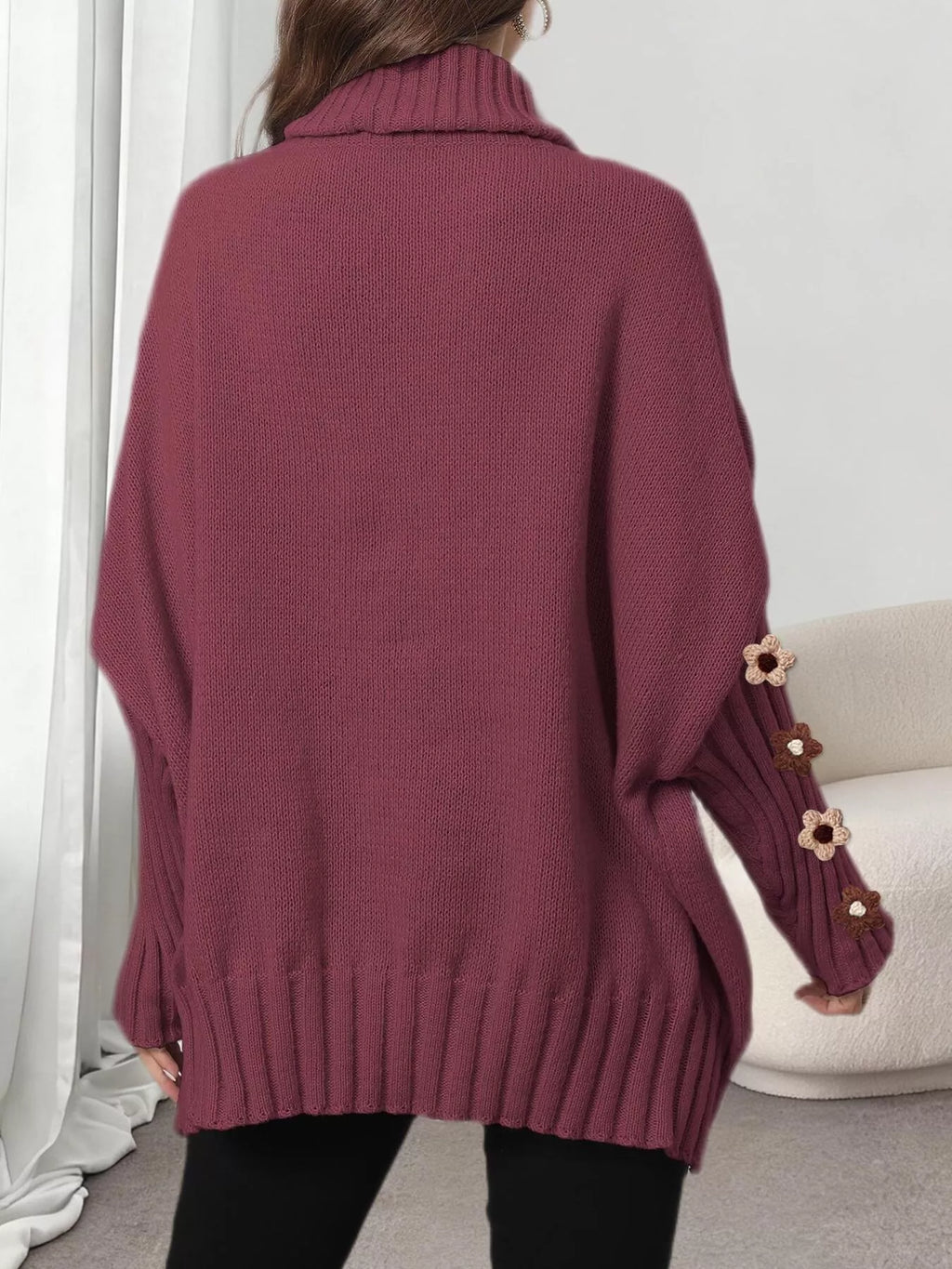 View 17 of the oversized turtleneck sweater with floral appliqué on the sleeves and ribbed collar and cuffs.