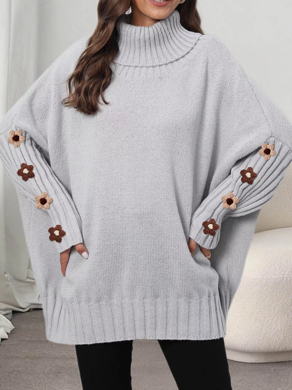 View 12 of the oversized turtleneck sweater with floral appliqué on the sleeves and ribbed collar and cuffs.