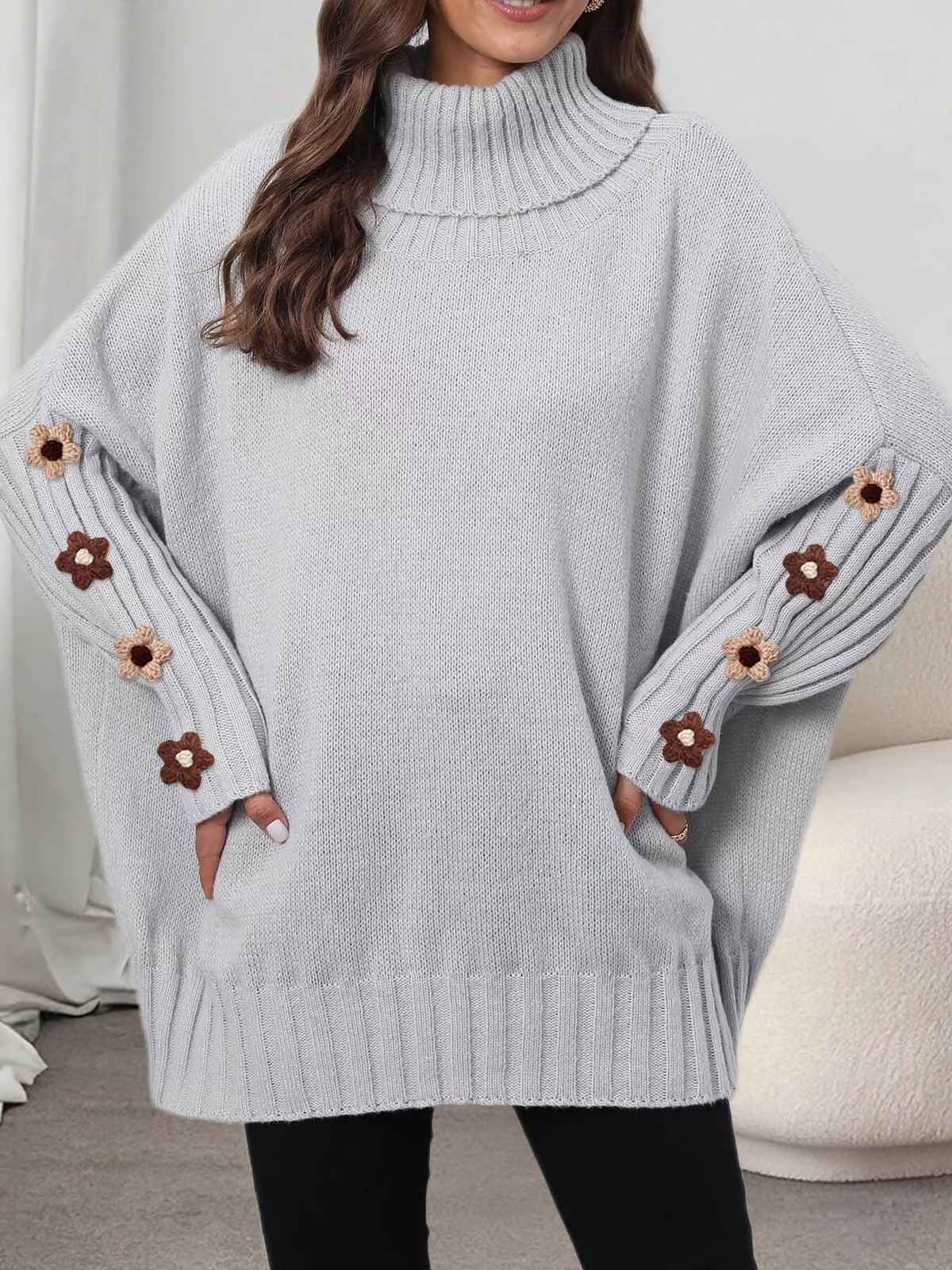 View 12 of the oversized turtleneck sweater with floral appliqué on the sleeves and ribbed collar and cuffs.