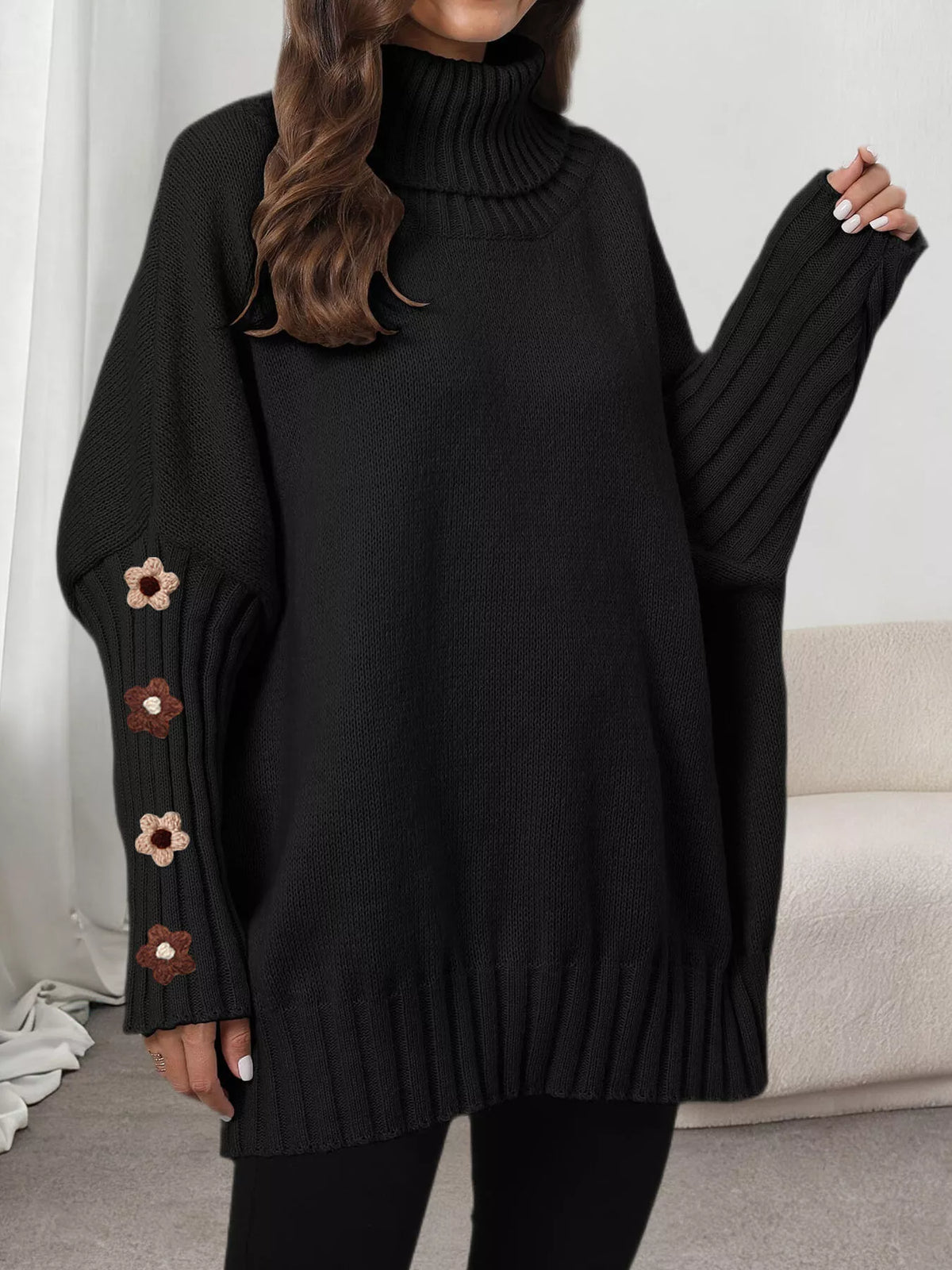 View 5 of the oversized turtleneck sweater with floral appliqué on the sleeves and ribbed collar and cuffs.