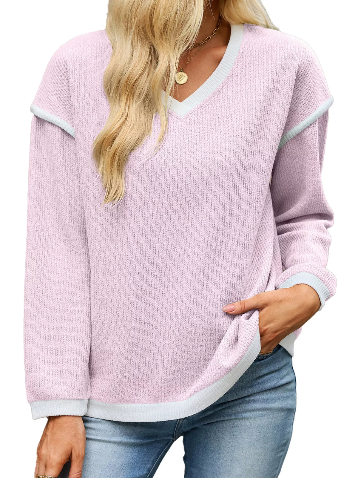 View 20 of the beige dropped-shoulder V-neck knit sweater with white binding at the neck, cuffs, and hem.