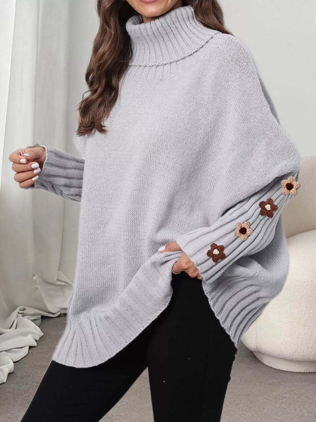 View 10 of the oversized turtleneck sweater with floral appliqué on the sleeves and ribbed collar and cuffs.