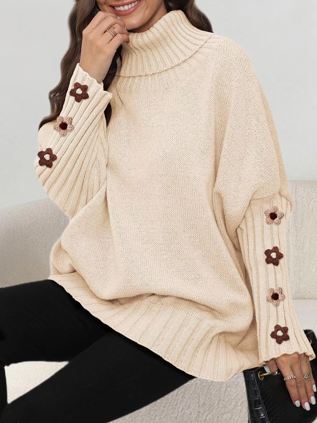 View 3 of the oversized turtleneck sweater with floral appliqué on the sleeves and ribbed collar and cuffs.