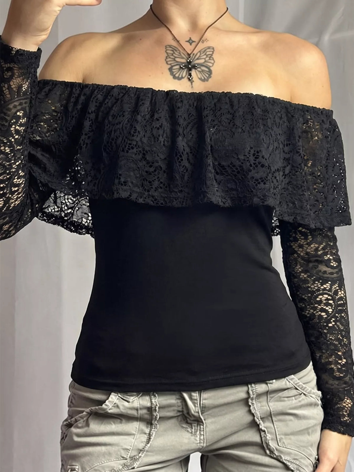 View 3 of the black off-the-shoulder crop top with floral lace at the neck and sleeves.