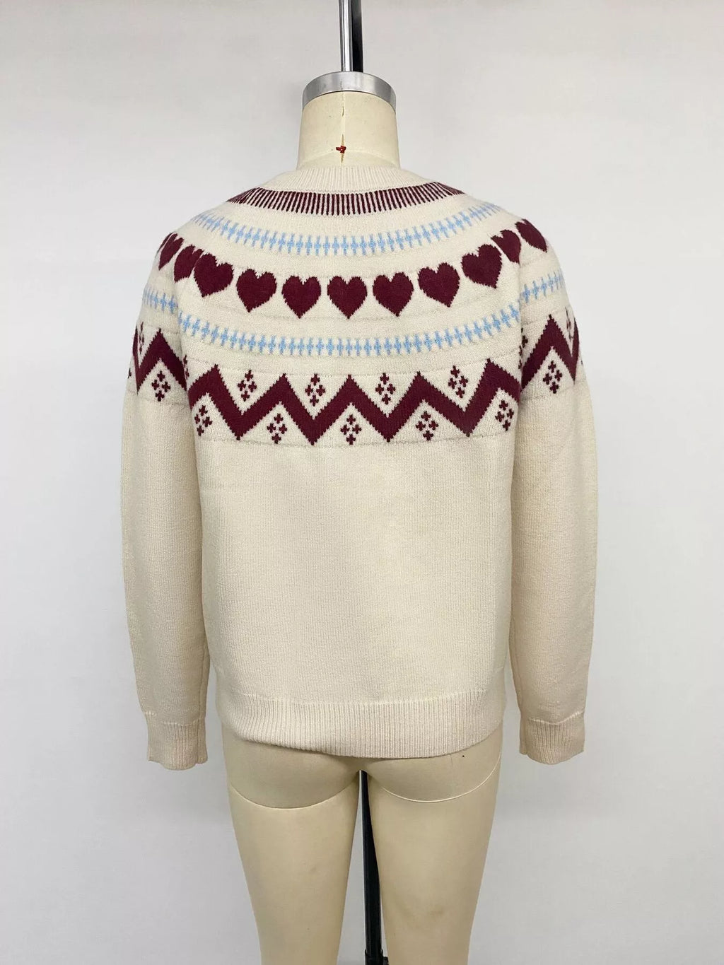 View 14 of the crewneck sweater with a heart pattern through the knit.