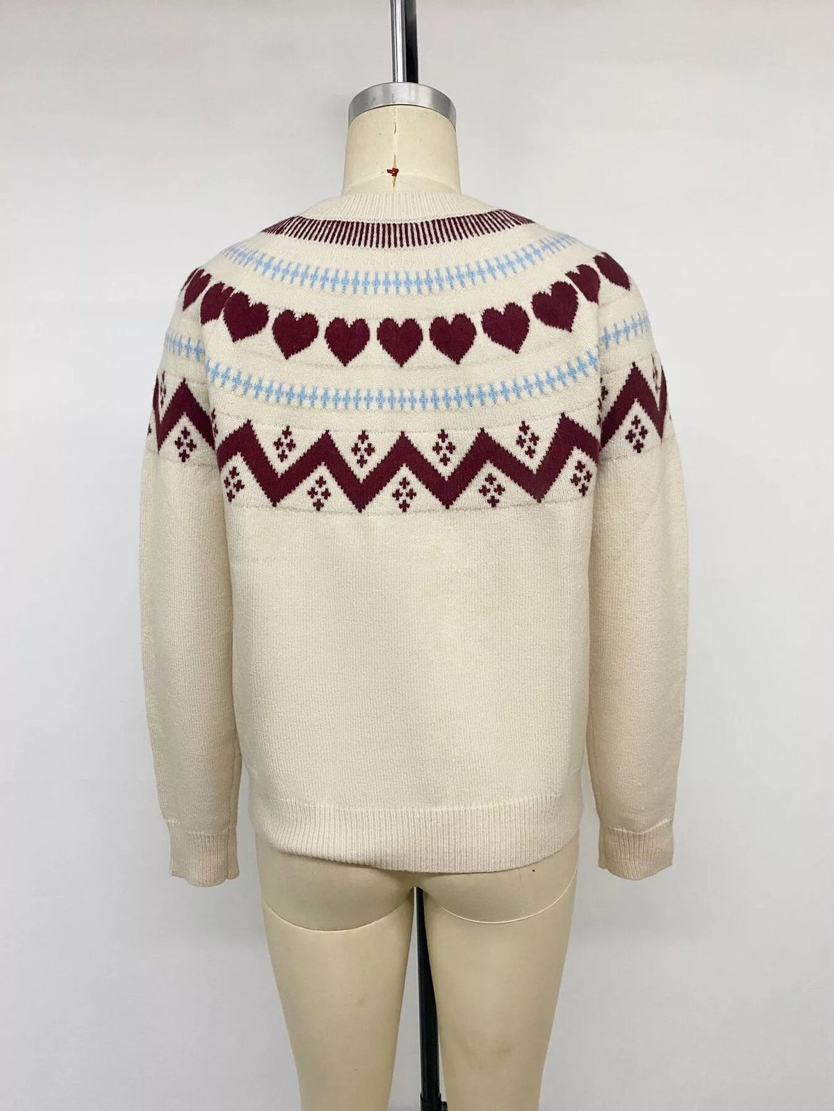 View 14 of the crewneck sweater with a heart pattern through the knit.