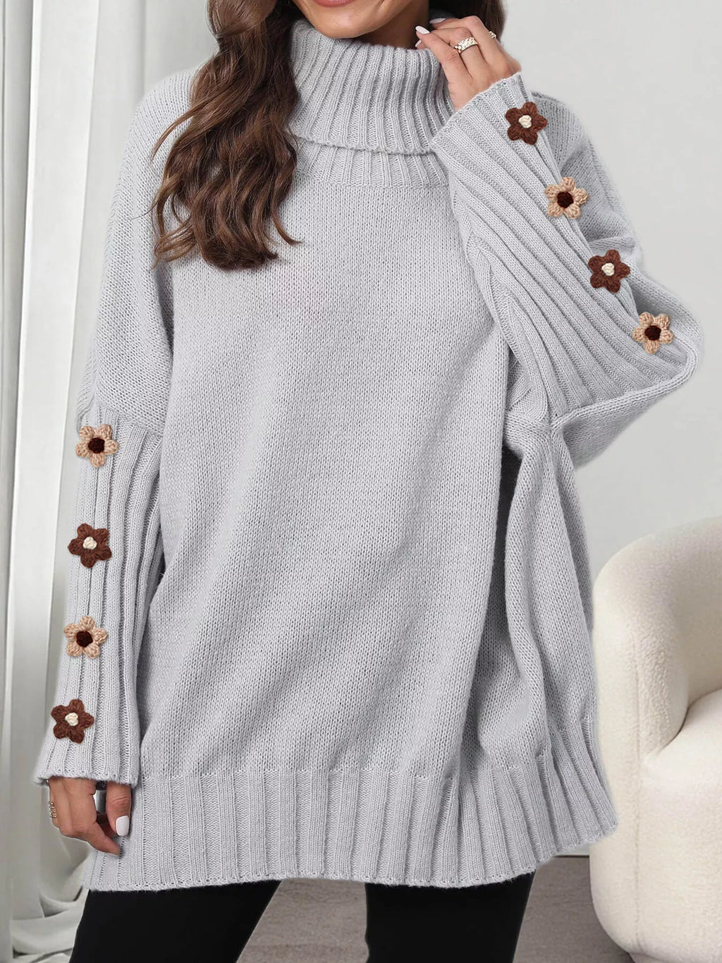 View 11 of the oversized turtleneck sweater with floral appliqué on the sleeves and ribbed collar and cuffs.