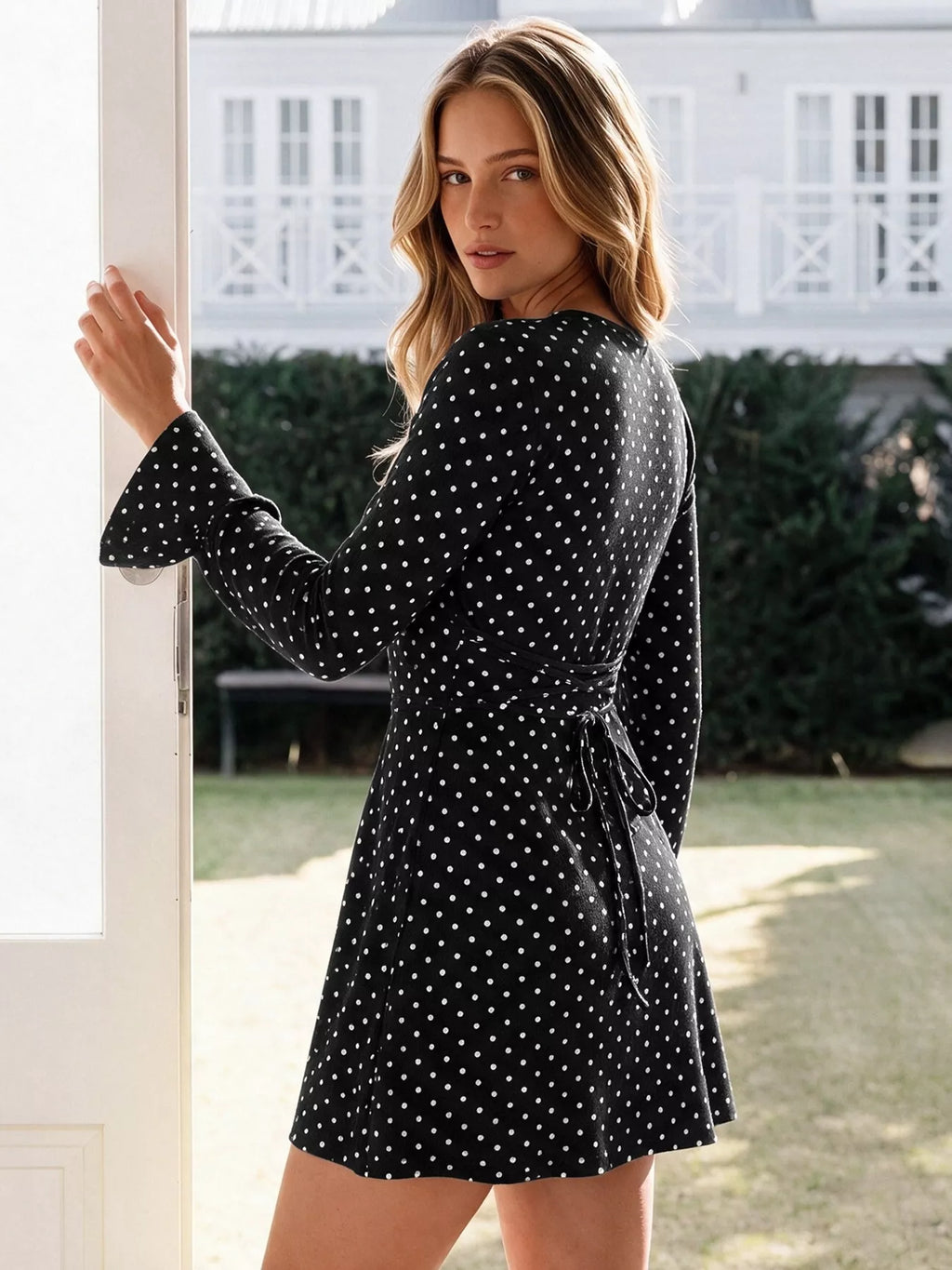 View 6 of the black long-sleeve polka-dot mini dress with a deep V and ruffled cuffs.