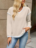 Beige dropped-shoulder V-neck knit sweater with white binding at the neck, cuffs, and hem.