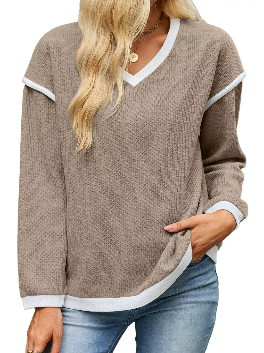 View 22 of the beige dropped-shoulder V-neck knit sweater with white binding at the neck, cuffs, and hem.