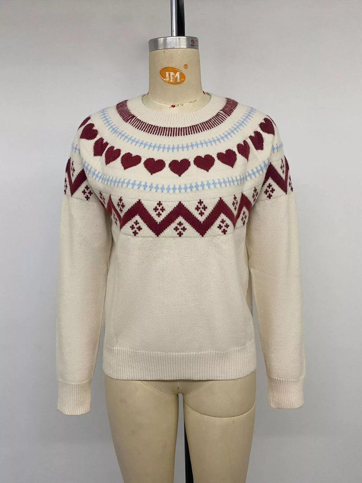 View 12 of the crewneck sweater with a heart pattern through the knit.