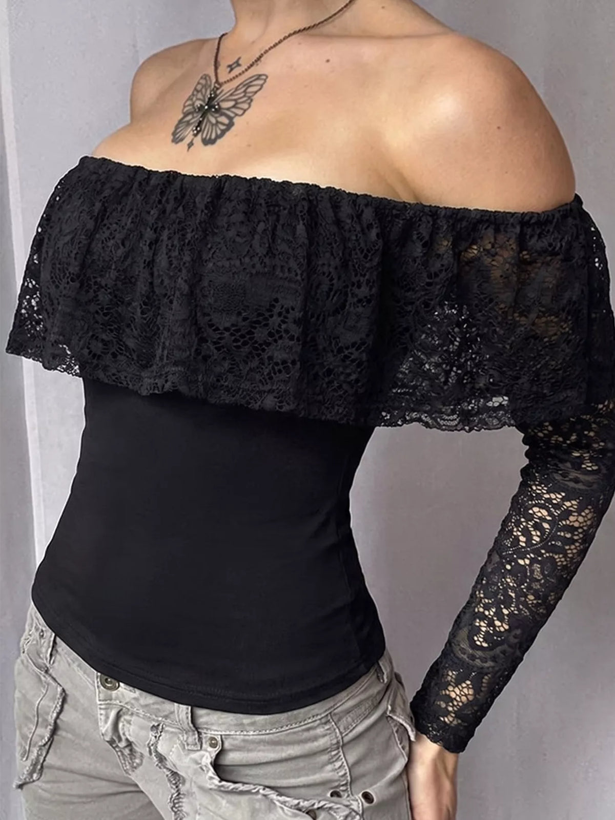 View 2 of the black off-the-shoulder crop top with floral lace at the neck and sleeves.