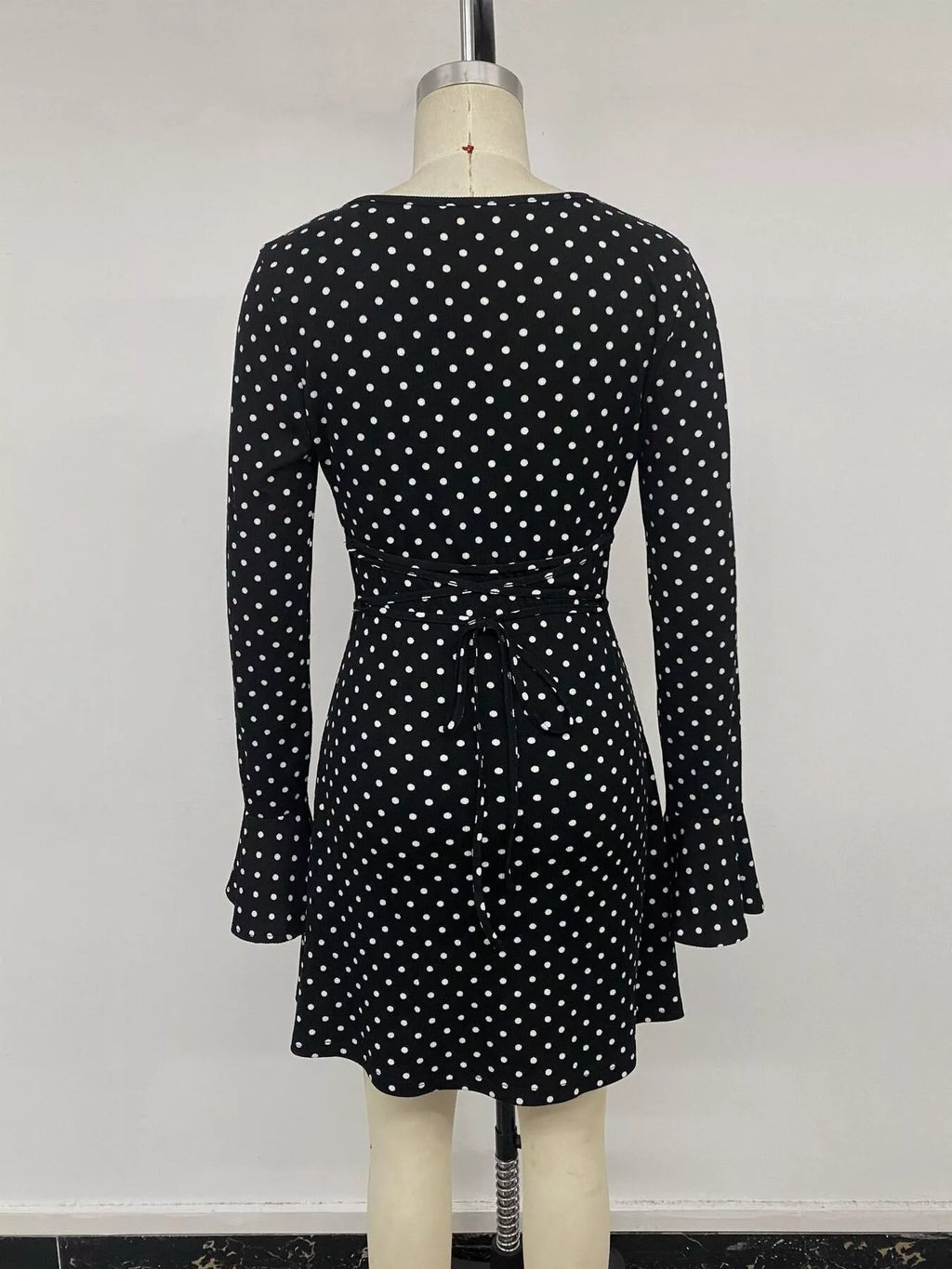 View 14 of the black long-sleeve polka-dot mini dress with a deep V and ruffled cuffs.
