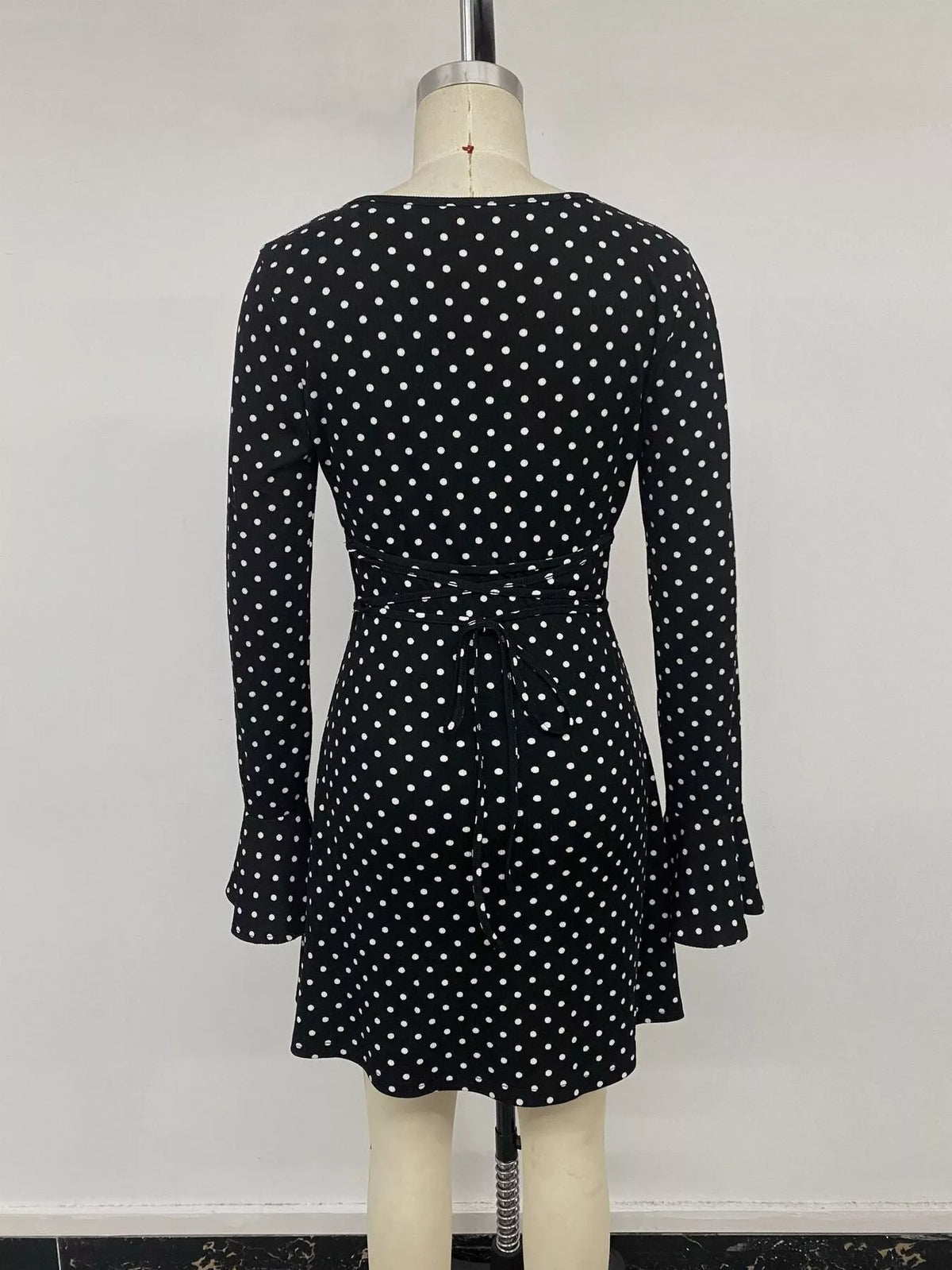 View 14 of the black long-sleeve polka-dot mini dress with a deep V and ruffled cuffs.